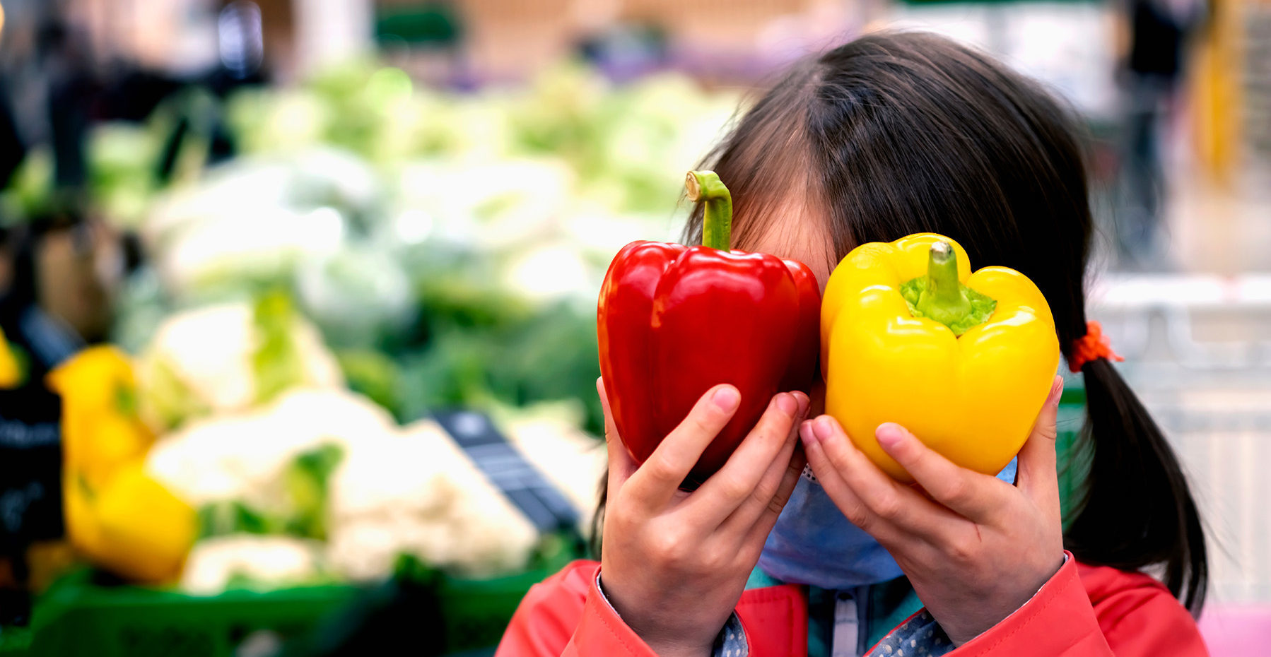 Girl with bell peppers in grocery store.