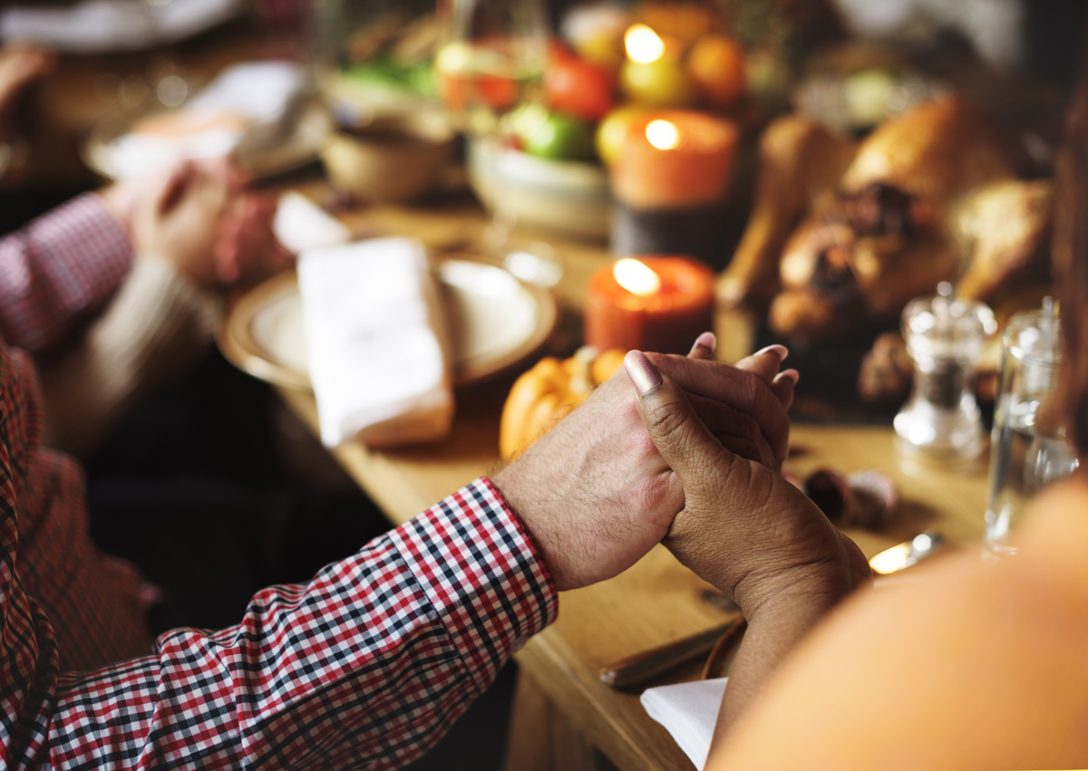 A family gives thanks around a table with food.