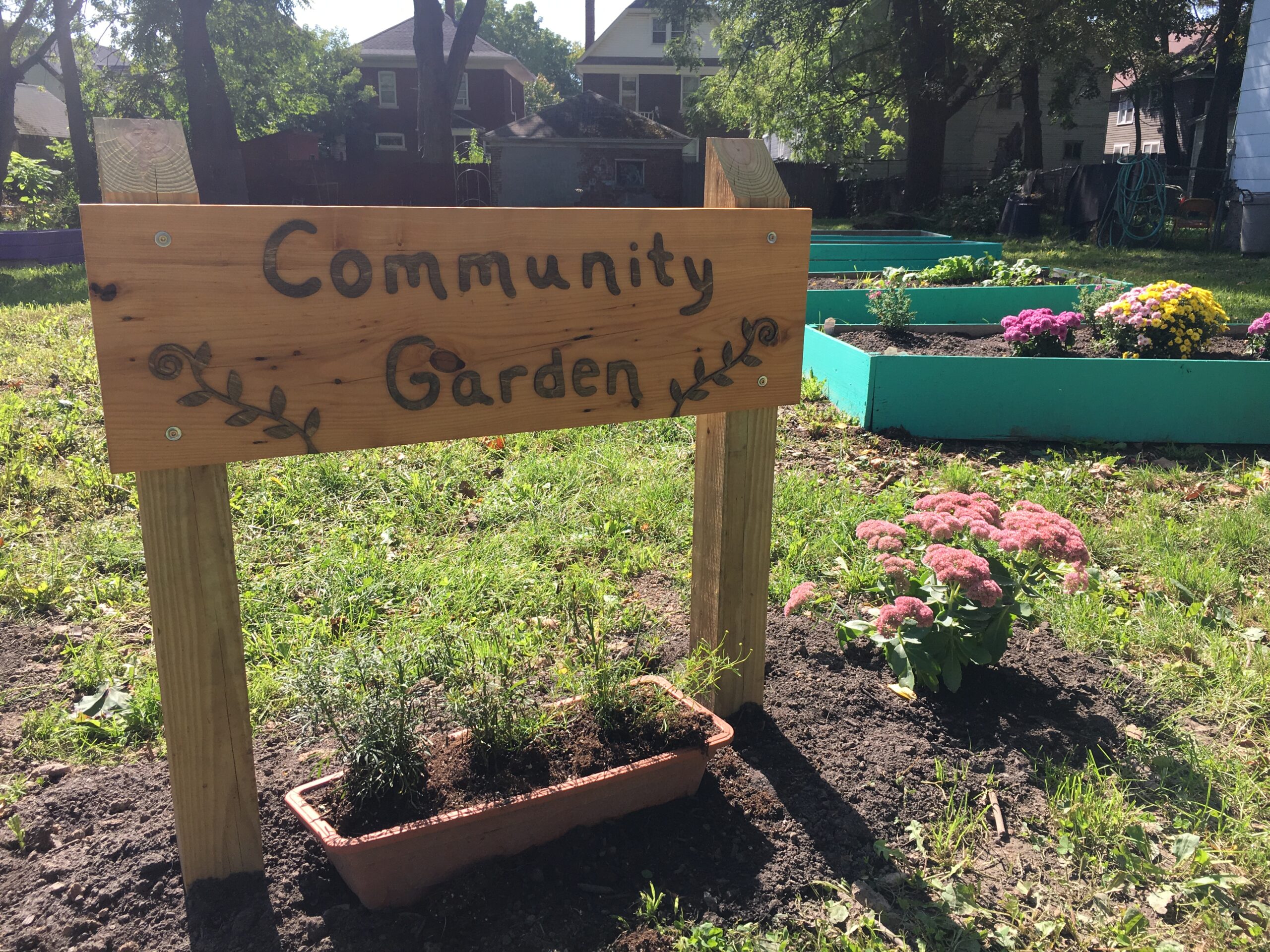 A wooden sign in front of a community garden in Niagara Falls.